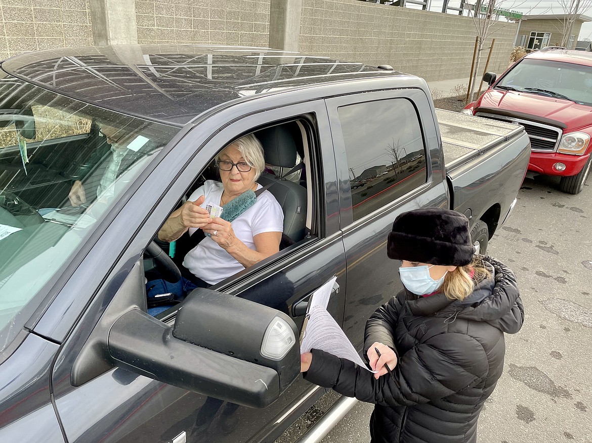 Galina Lutsenko, director of nursing services at Moses Lake Community Health Services, takes insurance and medical history information from Irene and Erv Gans as they wait to receive the first round of the Pfizer COVID-19 vaccine during a drive-through clinic at Quincy High School on Wednesday.