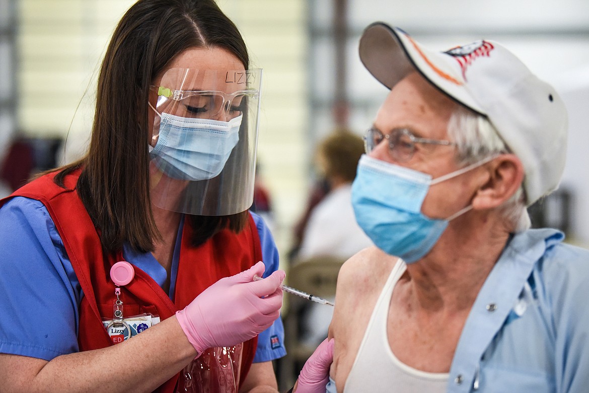 Lizzy Dwyer, left, an emergency room nurse with Kalispell Regional Healthcare, administers the COVID-19 vaccine to Norbert Tombarge, of Kalispell, at the Flathead County Fairgrounds on Thursday, Jan. 21. (Casey Kreider/Daily Inter Lake)