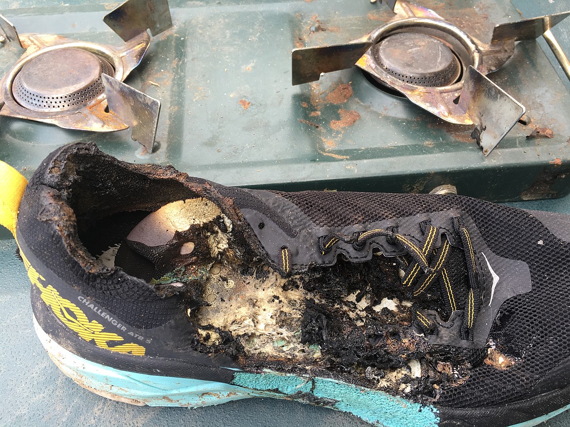 A torched Hoka Challenger ATR 5 sits next to the two-burner propane stove where the fire started that burned the shoe.