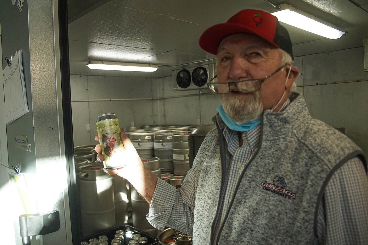 Quincy Public Market owner Larry Jones posing with an illustration of himself on Ancient Lakes Brewing Company's lager.