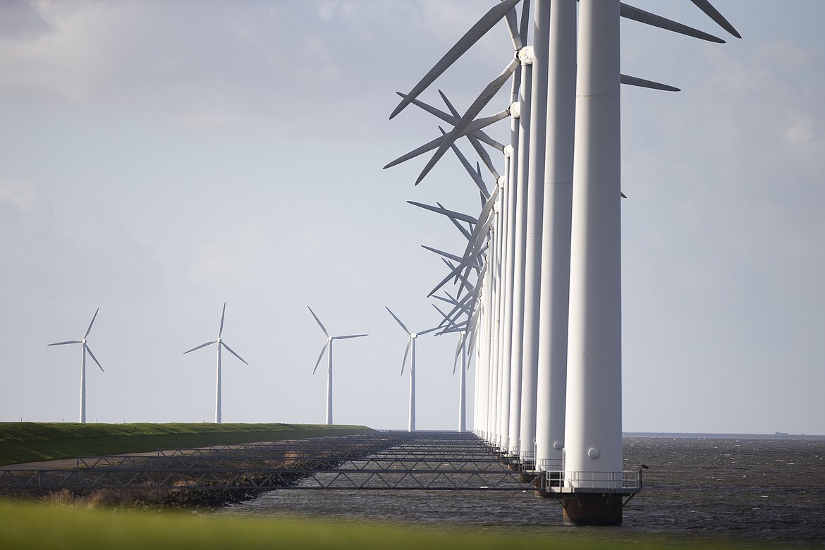 Wind turbines are seen on a dike near Urk, Netherlands, Friday, Jan. 22, 2021. A group of scientists, including five Nobel laureates, called Friday for more action to adapt the world to the effects of climate change, drawing comparisons with the faltering response to the coronavirus crisis, ahead of a major online conference on climate adaptation starting Monday and hosted by the Netherlands.