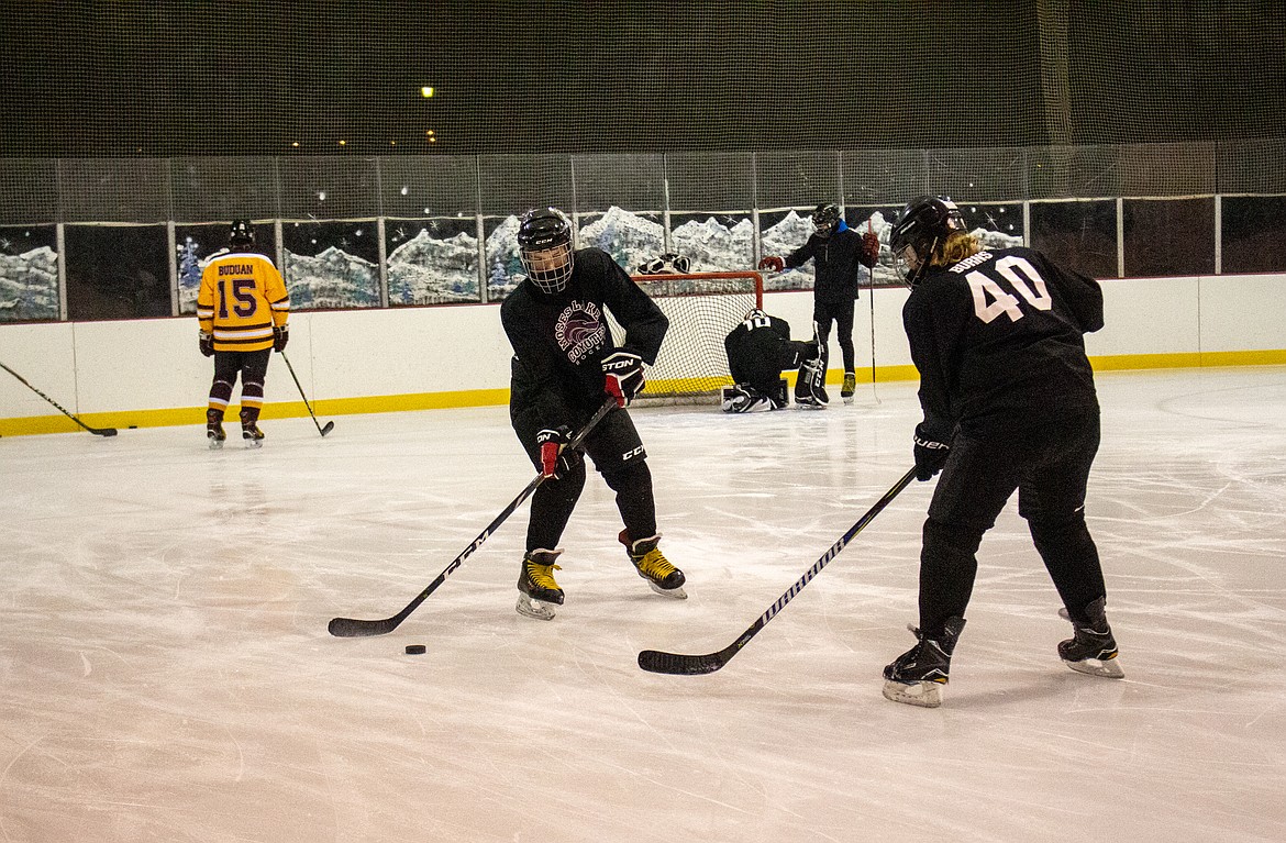 Mason Solders and Noah Burns work through a passing drill as they make their way around the ice at the Moses Lake Ice Rink on Monday evening.
