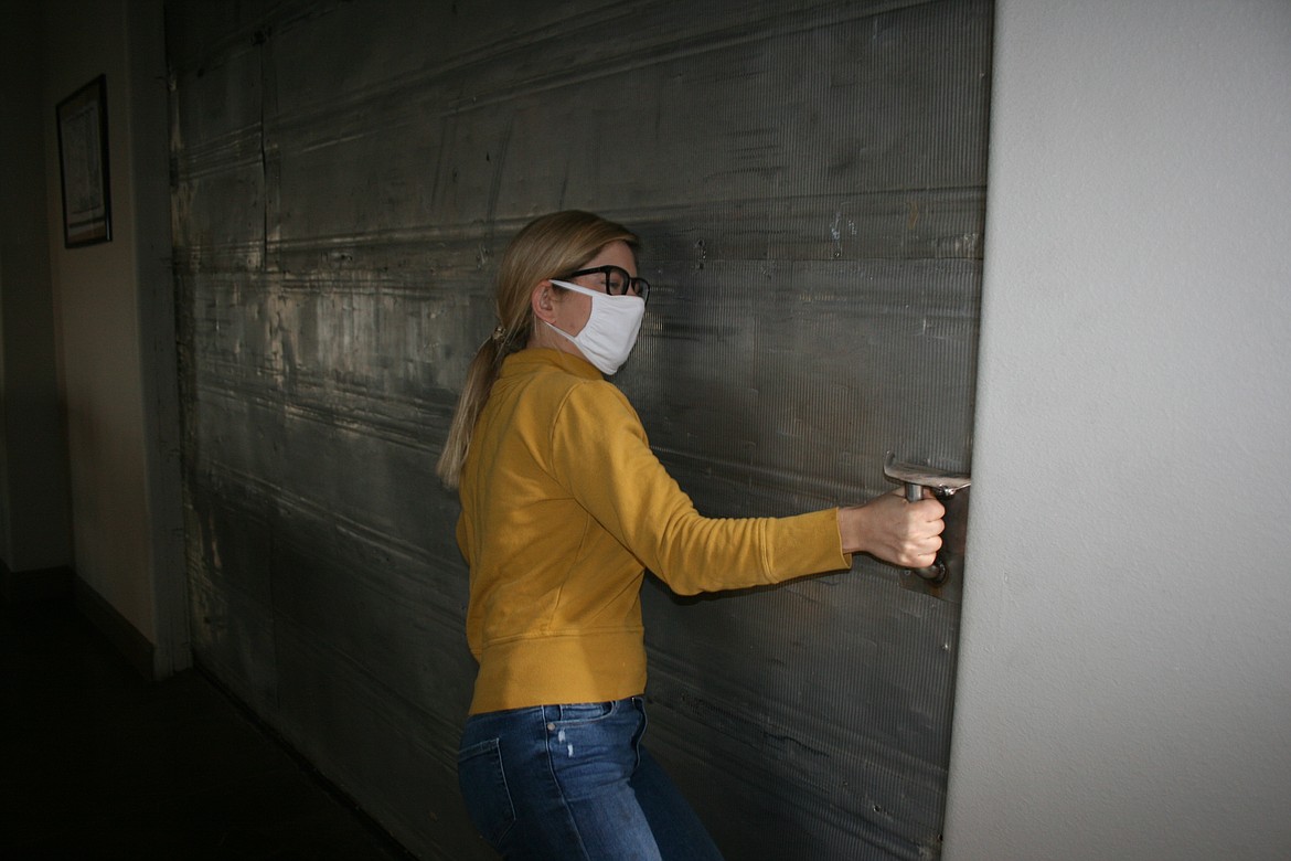 Ironworks Cafe owner Erika Rattray tugs on the oversize door that has allowed the restaurant to reopen for inside service.