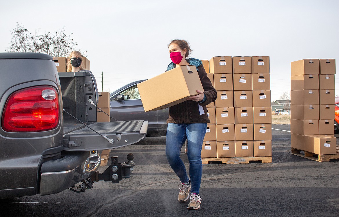 Volunteer Melissa Cazin loads a box of food into the back of a truck at the Farms to Families Food Box Dispersal at Moses Lake Christian Church on Thursday.