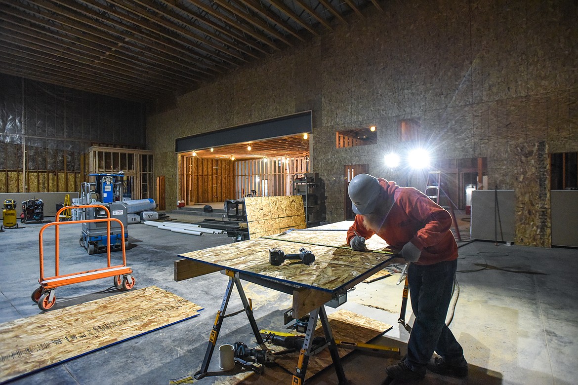 Gary Hawkins measures a piece of sheathing for a shear wall in the cafeteria at Ruder Elementary School in Columbia Falls on Tuesday, Jan. 26. In the background is an area that will become a music stage and performance area. (Casey Kreider/Daily Inter Lake)