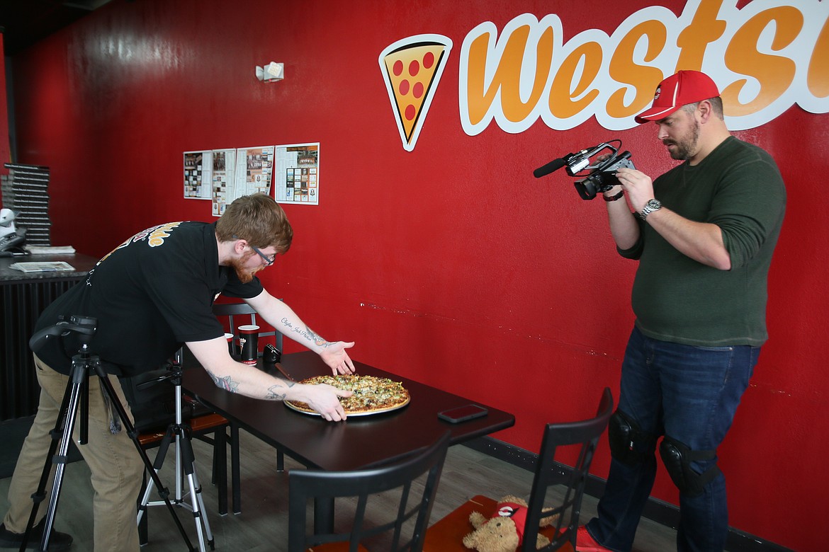 Post Falls Westside Pizza general manager Jason Pesikan serves a grand-sized Death by Pizza to YouTuber and professional eater Randy Santel as he films a piece for his channel on Thursday.