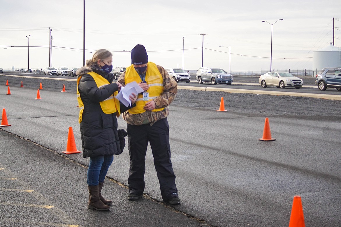 Samaritan transitions manager Angela Paxton and executive director of clinics Joe Ketter reviewing registration for the COVID-19 vaccine at the Grant County Fairgrounds on Saturday.