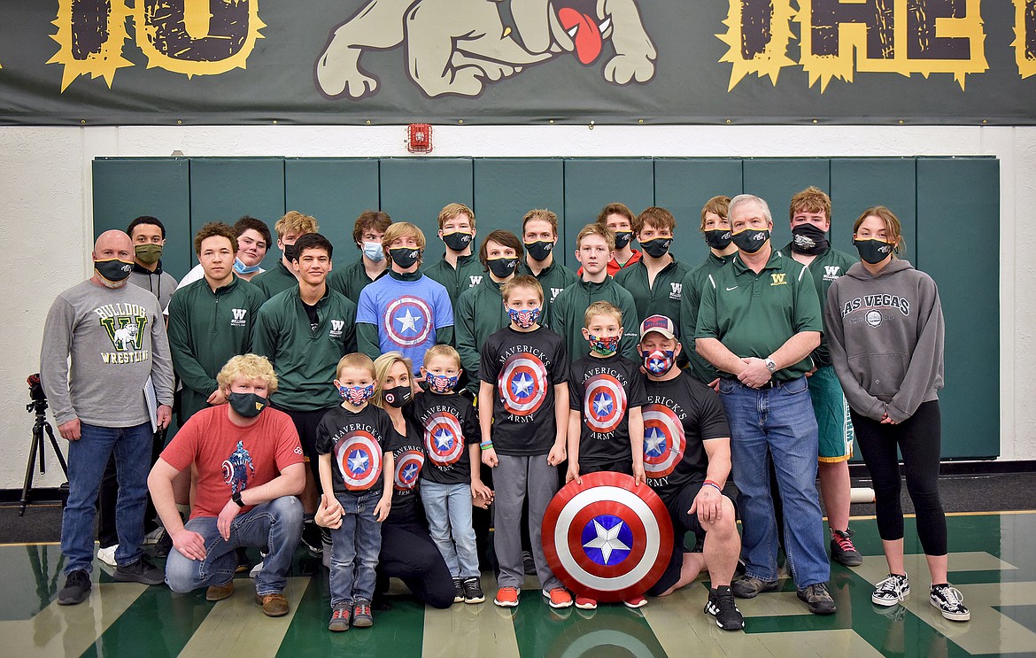 The Whitefish Wrestling team stands with the Bench family after their home dual on Saturday. Prior to the meet Whitefish had a moment of silence for Maverick Bench who recently lost his battle with a rare disease called Aplastic Anemia. His father Logan Bench wrestled for the Bulldogs in the late 1990s. (Whitney England/Whitefish Pilot)