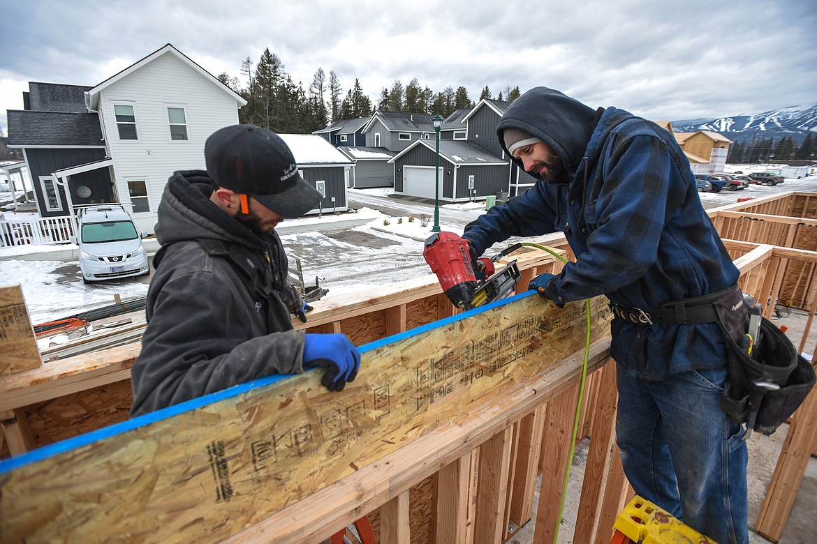Zack Lewis, left, and Victor Larson, subcontractors hired by Black Diamond Properties, install a rim board for a second-story floorbox in a home under construction at Trailview in Whitefish on Thursday, Feb. 4. (Casey Kreider/Daily Inter Lake)