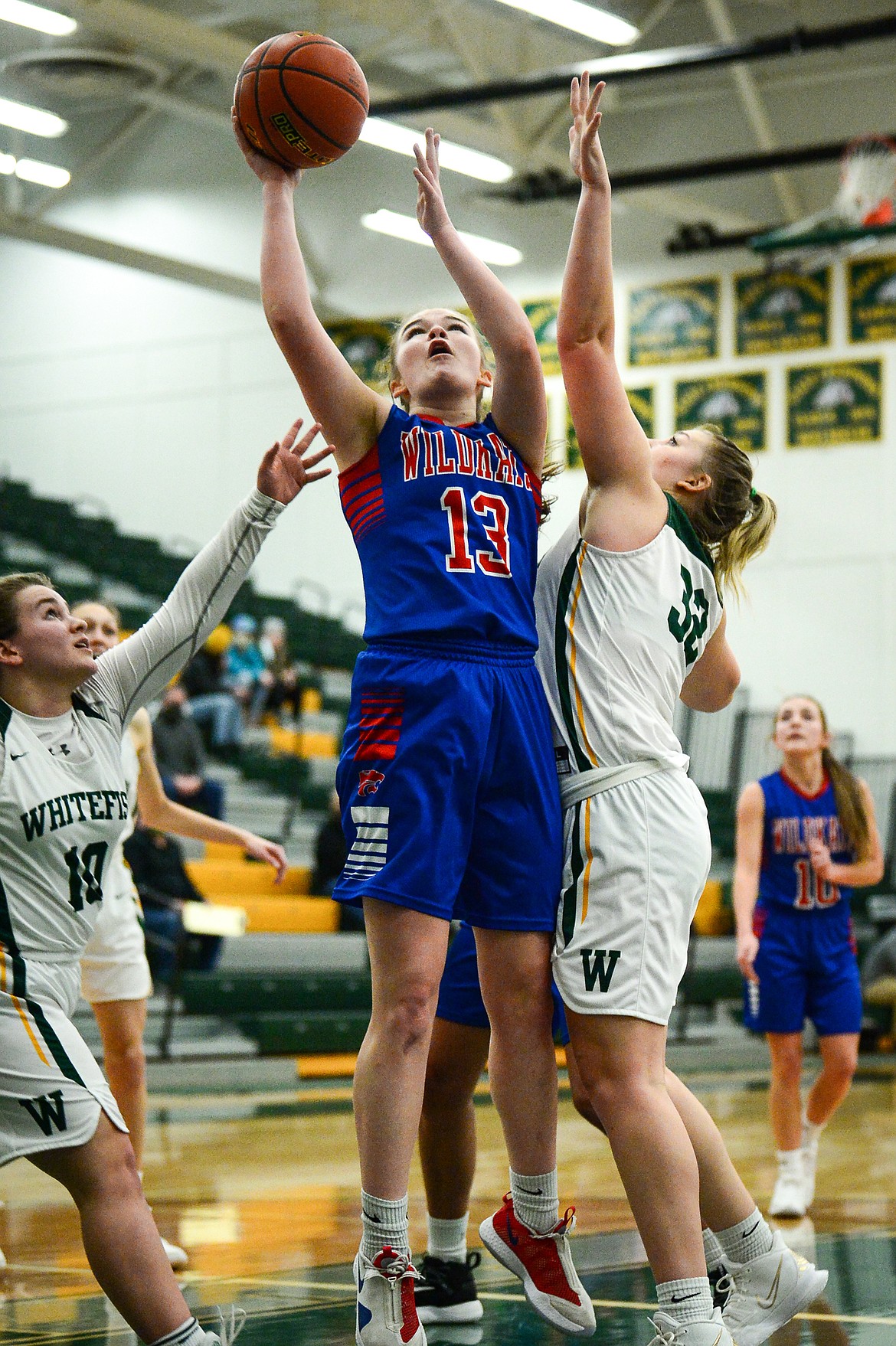Columbia Falls' Grace Gedlaman (13) goes to the basket between Whitefish's Ashton Ramsey (10) and Brook Smith (32) at Whitefish High School on Friday. (Casey Kreider/Daily Inter Lake)