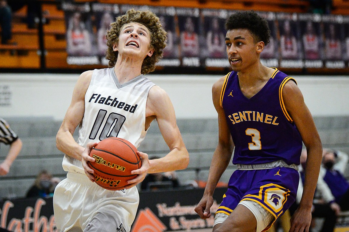 Flathead's Hunter Hickey (10) takes the ball to the basket ahead of Missoula Sentinel's Tony Frohlich-Fair (3) at Flathead High School on Saturday. (Casey Kreider/Daily Inter Lake)