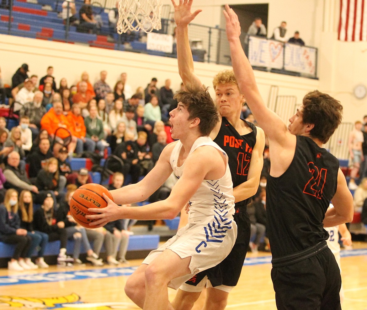 MARK NELKE/Press
Owen Smith of Coeur d'Alene soars in for a layup try as Isaac Ballew (12) and James Lee (21) of Post Falls defend Saturday at Viking Court.