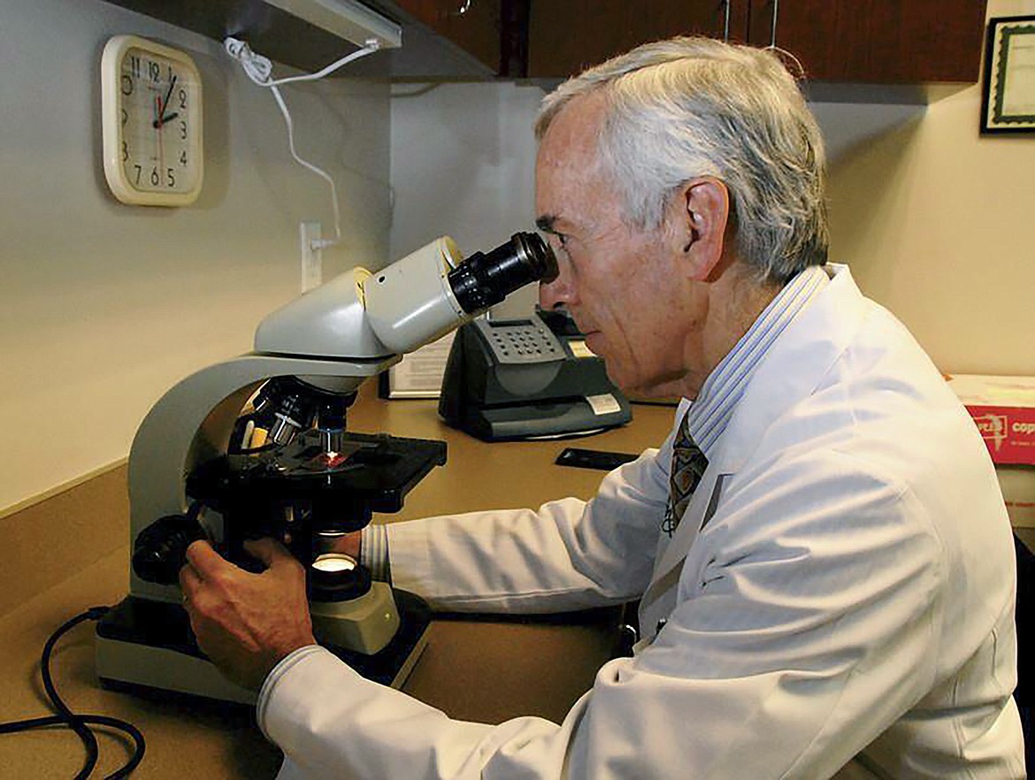 In this undated photo provided by Atlanta Allergy & Asthma, Dr. Stanley Fineman looks through a microscope at Atlanta Allergy & Asthma Center in Atlanta to examine the pollen. When Fineman started 40 years ago as an allergist in Atlanta, he told patients they should start taking their medications and prepare for the onslaught of pollen season around St. Patrick’s Day. Now he tells them to start around St. Valentine’s Day.