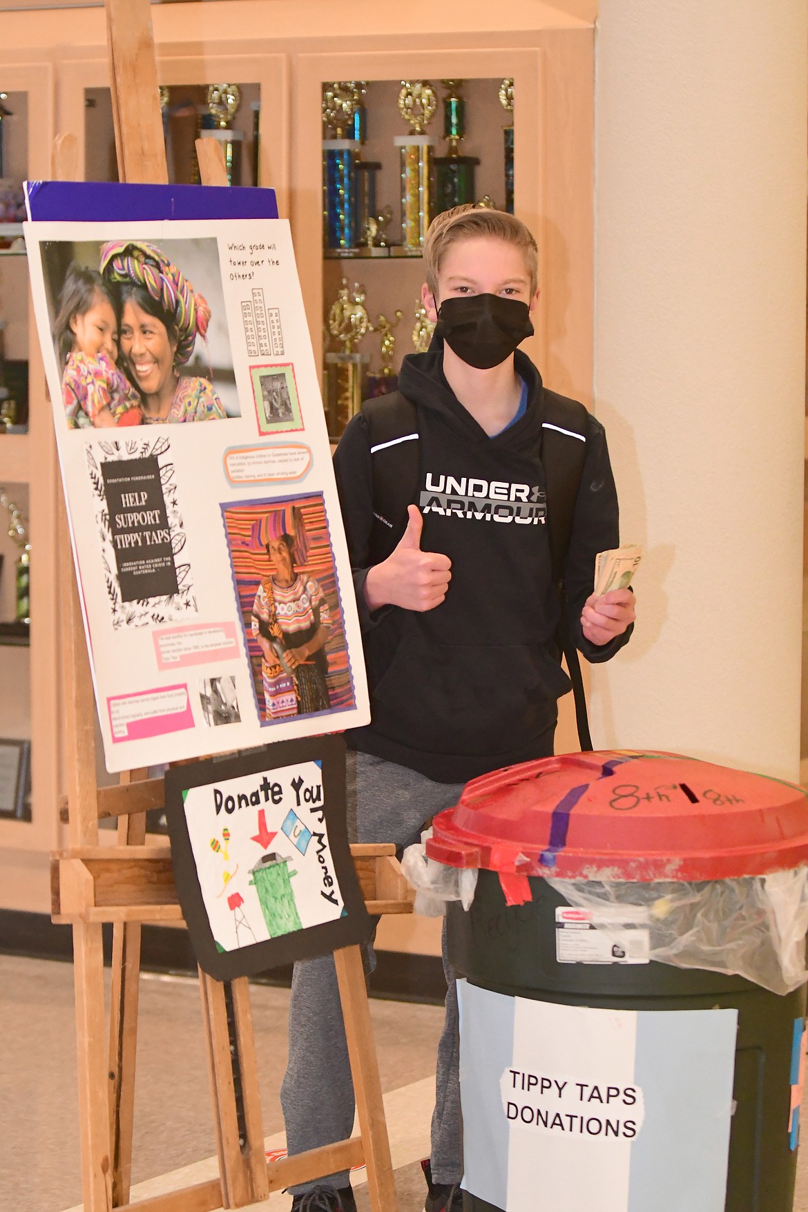 Columbia Falls eighth grader Carson Settles makes a donation Friday morning to help fund handwashing stations in Guatemala. (Teresa Byrd/Hungry Horse News)