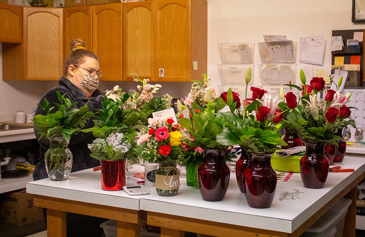 Stevee Lincoln, designer for Floral Occasions in Moses Lake, works on flower arrangements on Wednesday morning with her workspace nearly already filled up early in the day.