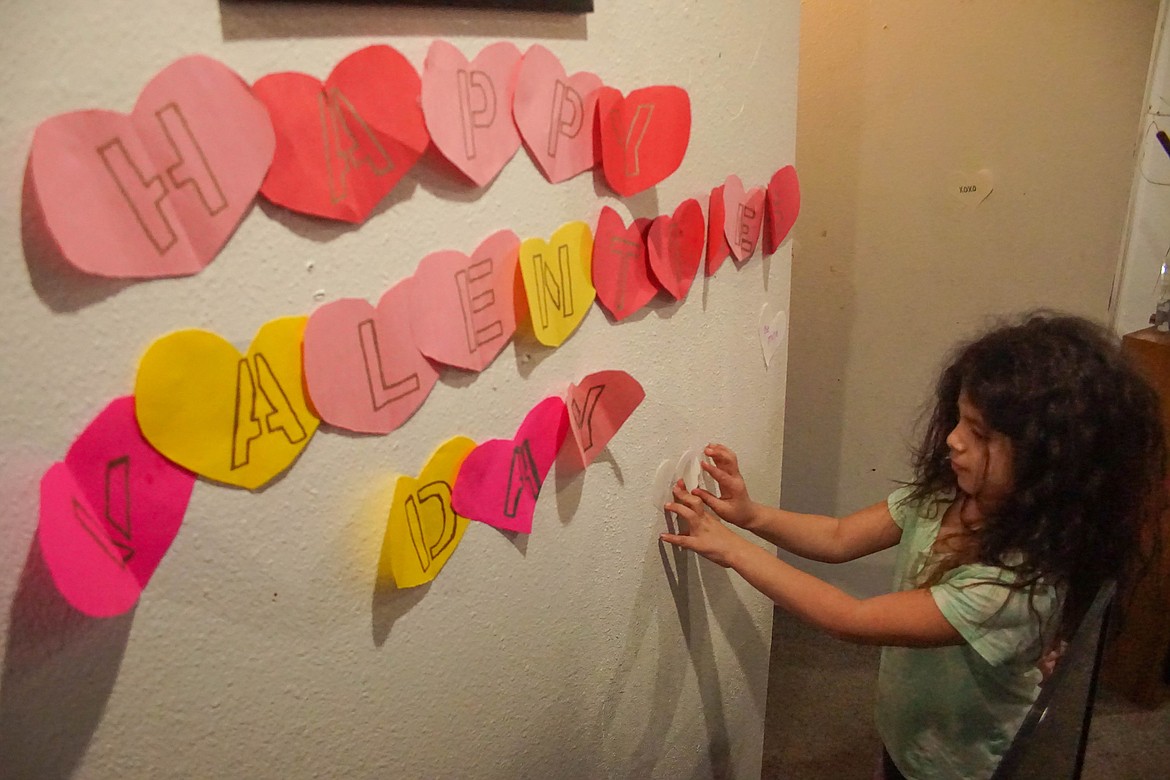 Larson Heights Elementary School student Alieonna Favors hangs decorations at an at-home Valentine's Day party on Friday.