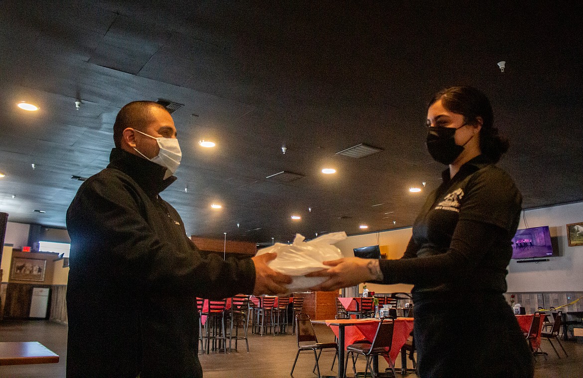 Valentin Santiago, left, receives his takeout order from Makayla Mendoza at Andaluz de Quincy on South Central Avenue in Quincy on Monday afternoon.