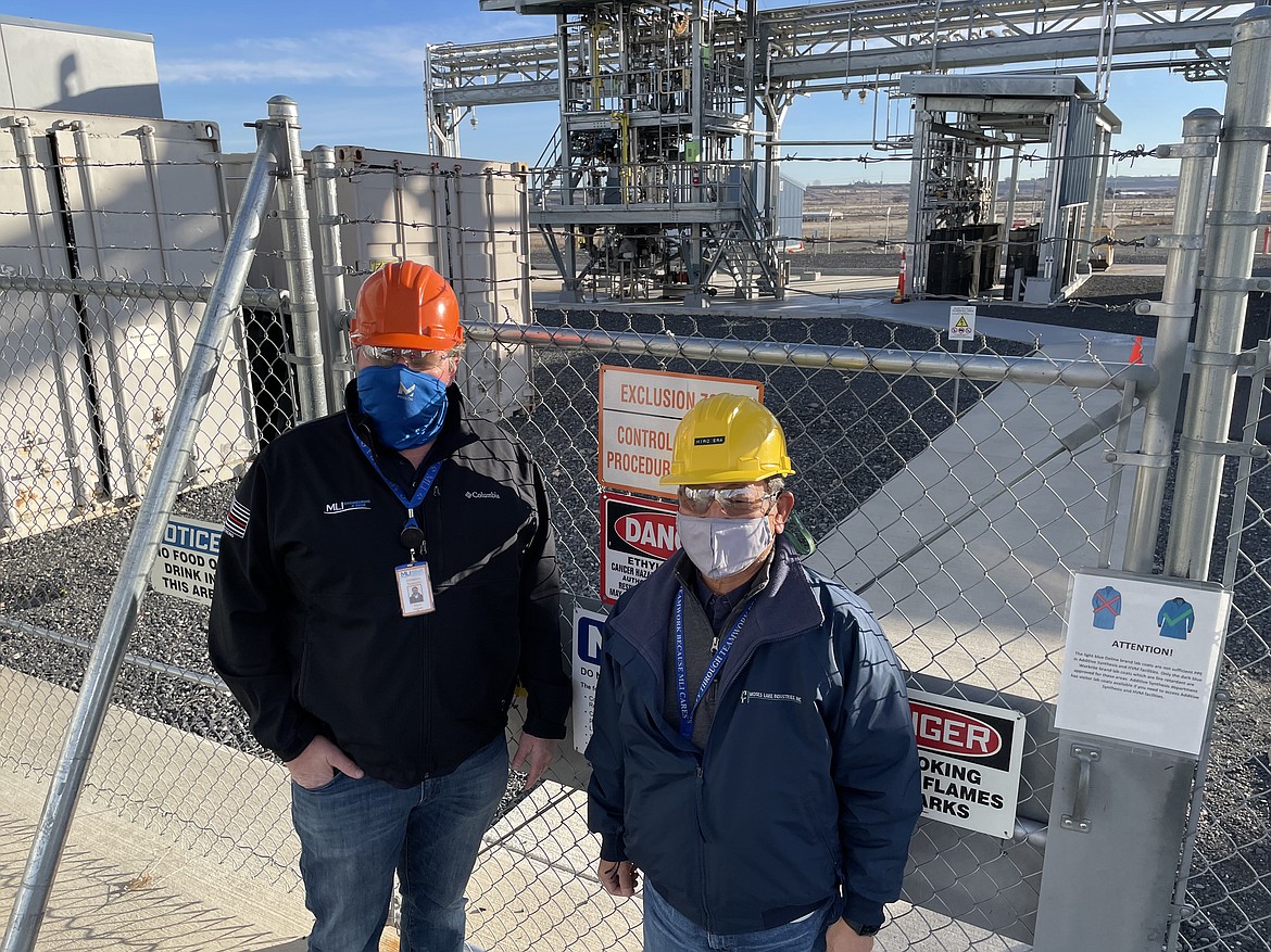 Moses Lake Industries Vice President of Operations Brent Hansen, left, and President Hiroyuki Era stand in front of the company’s polymer reaction unit in December.