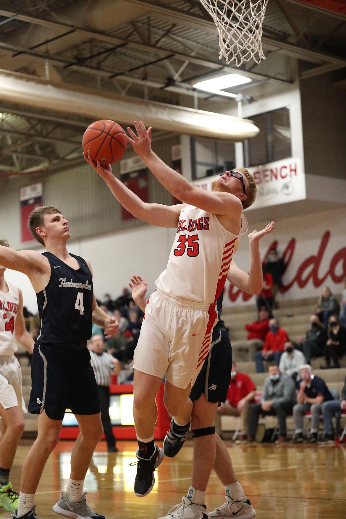 Junior Ethan Butler splits a pair of Lake City defenders and attempts a contested layup on Tuesday.