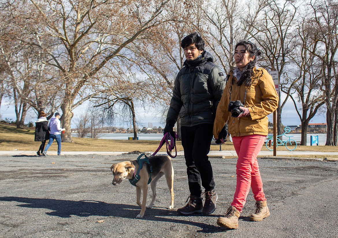Samuel Villanueva and Scarlett Olivares walk their dog, Luna, at Blue Heron Park in Moses Lake on Monday afternoon.