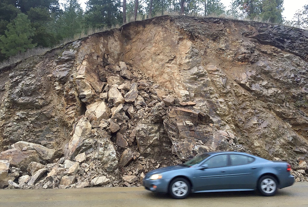 A car on Monday passes by a hillside along Fernan Lake Road where a rockslide occurred Saturday night