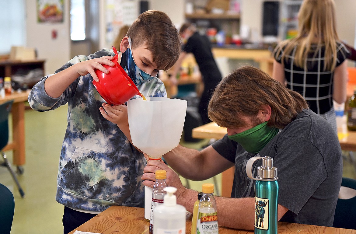 CSE Facilities and Grounds Coordinator Chris Bickford helps sixth grader Nick Barker pour his team's salad dressing into a bottle for the competition. (Whitney England/Whitefish Pilot)