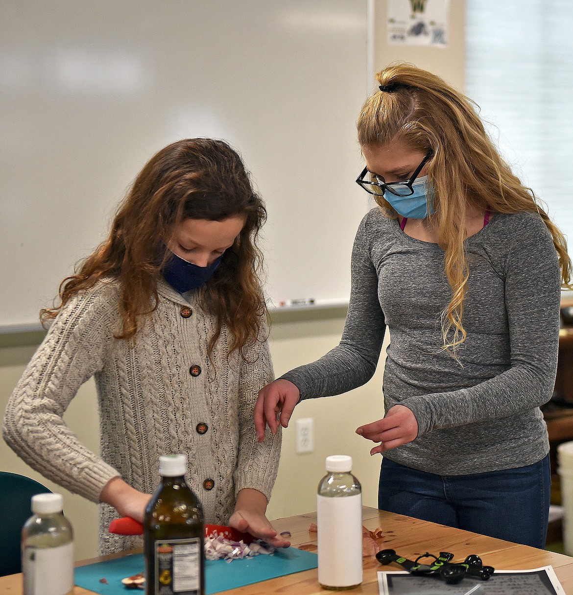 Sixth graders Alina Pohlman and Jaclyn Tucker chop onions for their dressing durning the Salad Dressing Tournament at the CSE. (Whitney England/Whitefish Pilot)