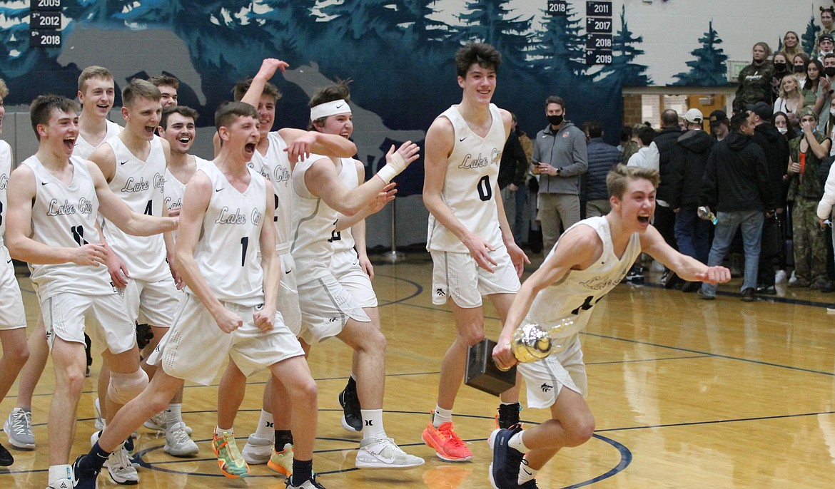 MARK NELKE/Press
Kolton Mitchell (14) races with the trophy toward the student section to celebrate after Lake City beat Post Falls to win the 5A Region 1 boys basketball championship Tuesday night at Lake City.