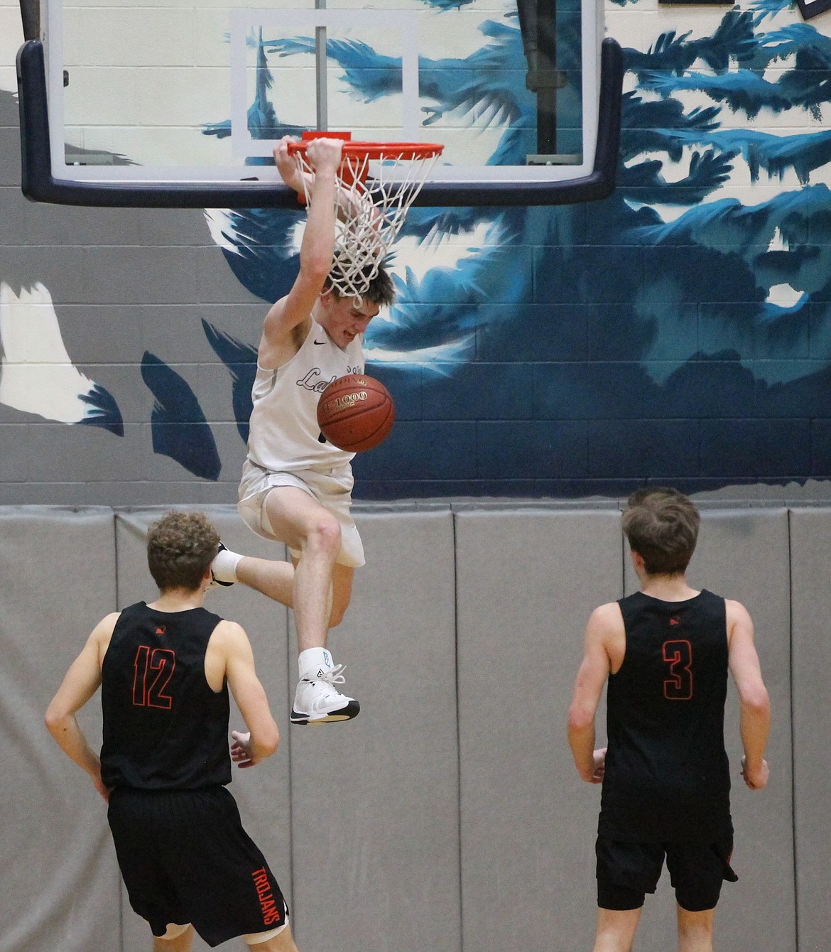 MARK NELKE/Press
Zach Johnson of Lake City dunks in the second half as Isaac Ballew (12) and Caden McLean (3) of Post Falls look on Tuesday night in the 5A Region 1 boys basketball championship game at Lake City.