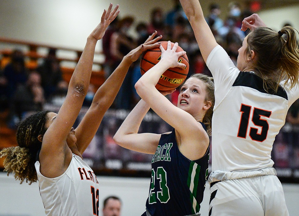 Glacier's Janessa Henson (23) drives to the basket between Flathead's Akilah Kubi (12) and Clare Converse (15) at Flathead High School on Thursday. (Casey Kreider/Daily Inter Lake)