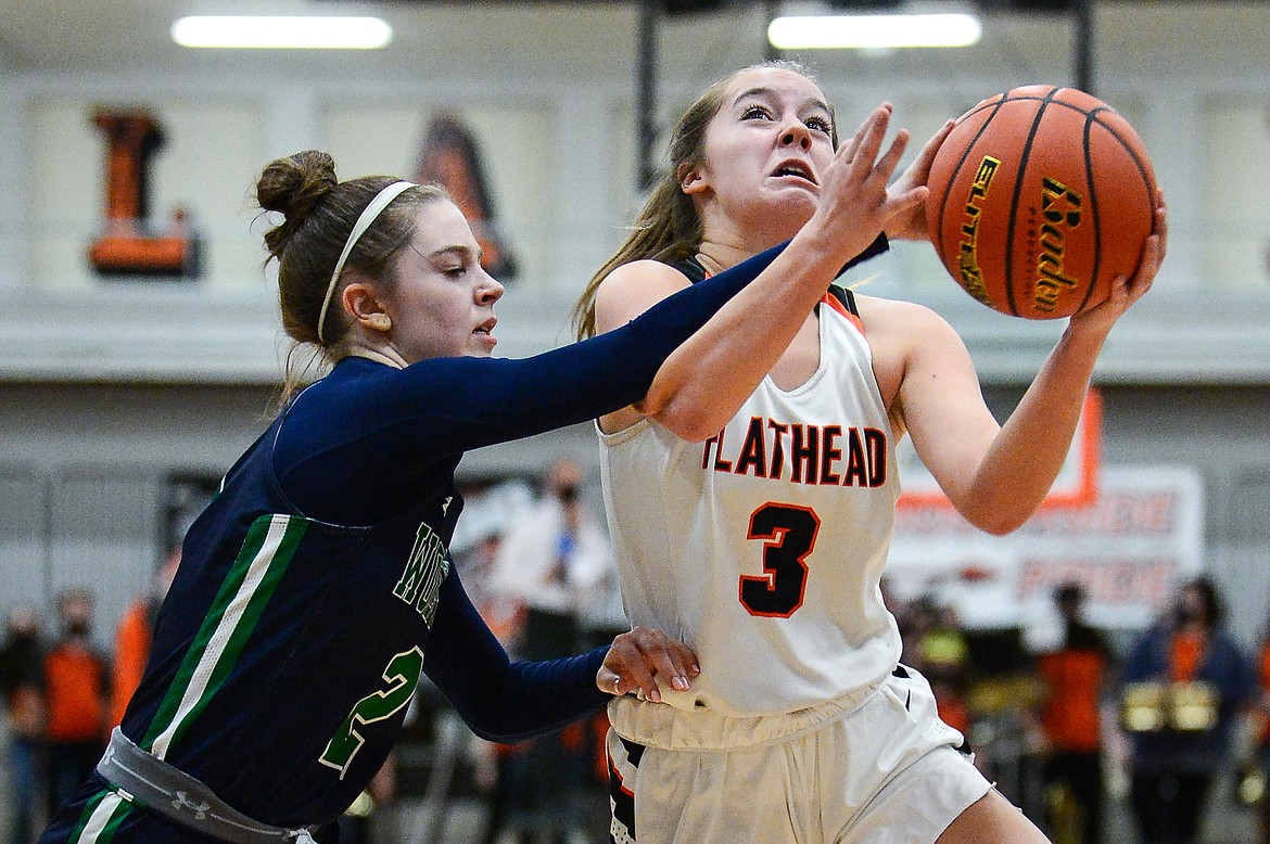 Flathead's Kuyra Siegel (3) draws a foul from Glacier's Sidney Gulick (2) on her way to the basket at Flathead High School on Thursday. (Casey Kreider/Daily Inter Lake)