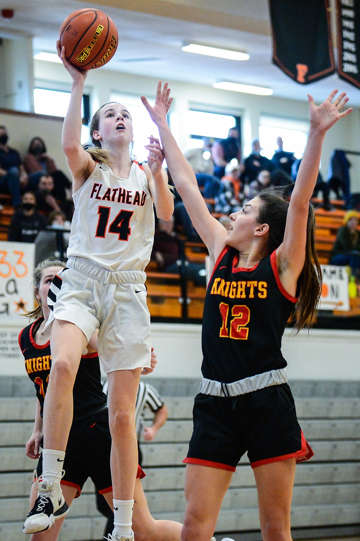 Flathead's Kennedy Moore (14) drives to the basket guarded by Missoula Hellgate's Perry Paffhausen (12) at Flathead High School on Saturday. (Casey Kreider/Daily Inter Lake)