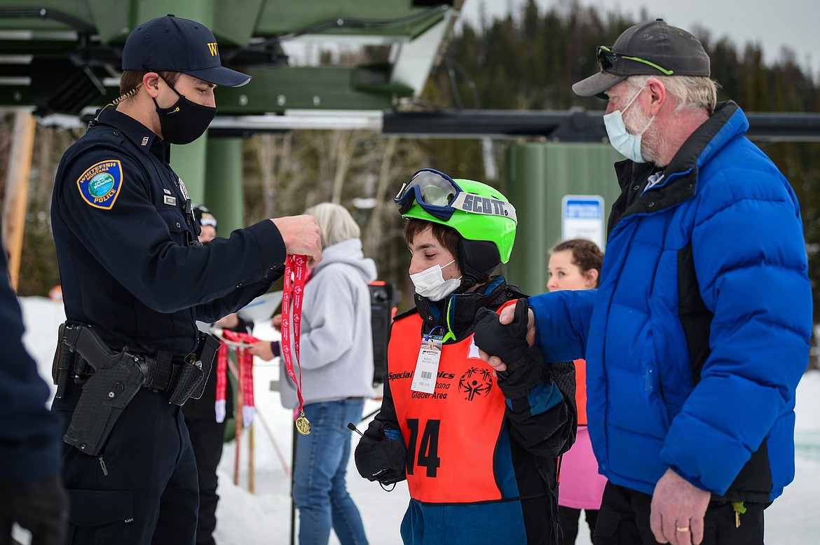 Jeffrey Sagen, center, with the Whitefish Schools team, receives a medal for the Alpine Giant Slalom event from officer Trey Nasset with the Whitefish Police Department, during the Special Olympics Montana Winter Games at Whitefish Mountain Resort on Tuesday. (Casey Kreider/Daily Inter Lake)