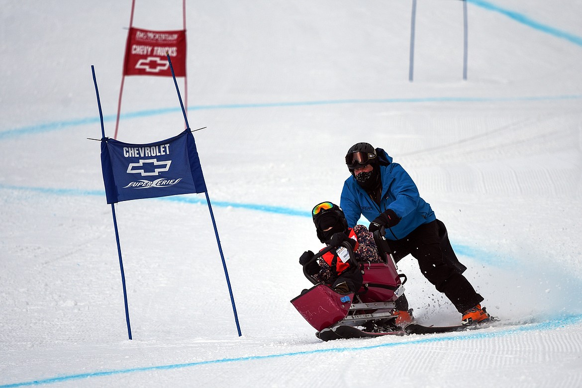 Rebecka McIntyre, with the Flathead Industries team, weaves through the Alpine Novice Giant Slalom course on a sit ski with DREAM Adaptive instructor Chris Pilosoph at the Special Olympics Montana Winter Games at Whitefish Mountain Resort on Tuesday. (Casey Kreider/Daily Inter Lake)