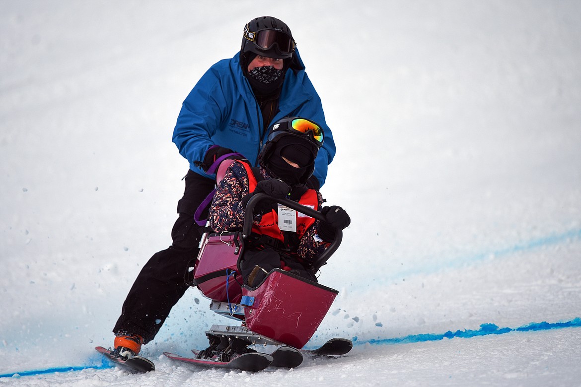 Rebecka McIntyre, with the Flathead Industries team, crosses the finish line on a sit ski on the Alpine Novice Giant Slalom course with DREAM Adaptive instructor Chris Pilosoph at the Special Olympics Montana Winter Games at Whitefish Mountain Resort on Tuesday. (Casey Kreider/Daily Inter Lake)