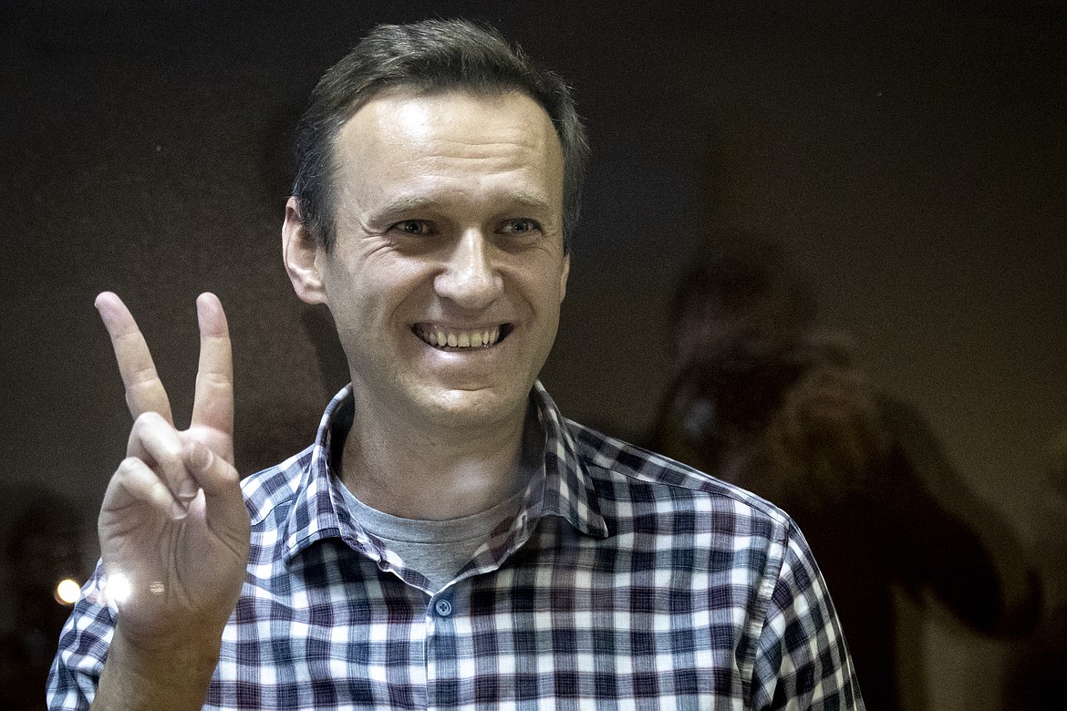 In this Saturday, Feb. 20, 2021 file photo, Russian opposition leader Alexei Navalny gestures as he stands behind a grass of the cage in the Babuskinsky District Court in Moscow, Russia. Russian opposition leader Alexey Navalny was transported to a prison 100km away from Moscow. Navalny was taken to a prison in Pokrov city after Moscow city court rejected appeal against his prison sentence on Saturday, Feb. 27, 2021.