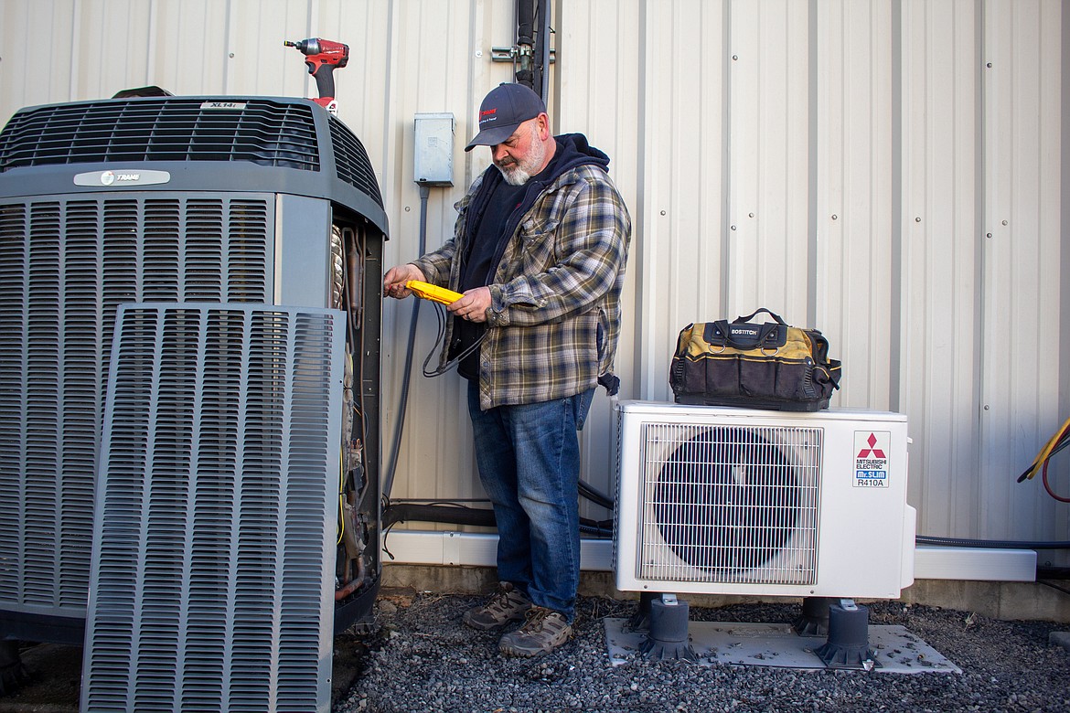 Polhamus Heating & Air Conditioning service manager Dave Carlson demonstrates their typical maintenance routine on a unit outside the office building on Bell Road Northeast in Moses Lake on Wednesday.