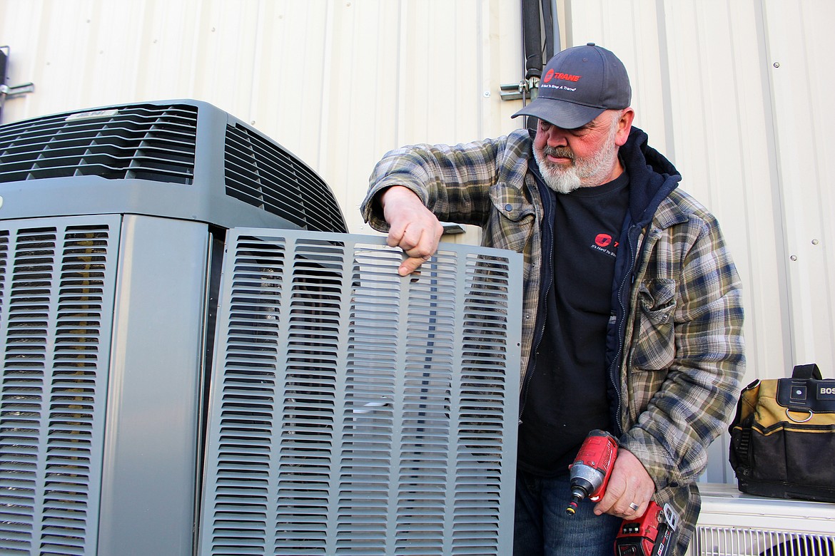 Dave Carlson opens up a HVAC unit outside the Polhamus office building in Moses Lake on Wednesday to showcase the inside coils and some of the areas they inspect on maintenance jobs this time of year.