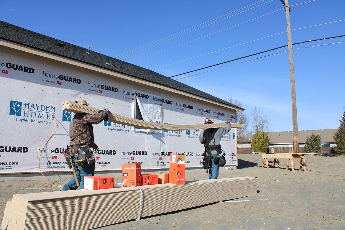 Tabo Miranda, left, and Gustavo Silva haul siding around 713 N. Hooper Drive, Moses Lake.