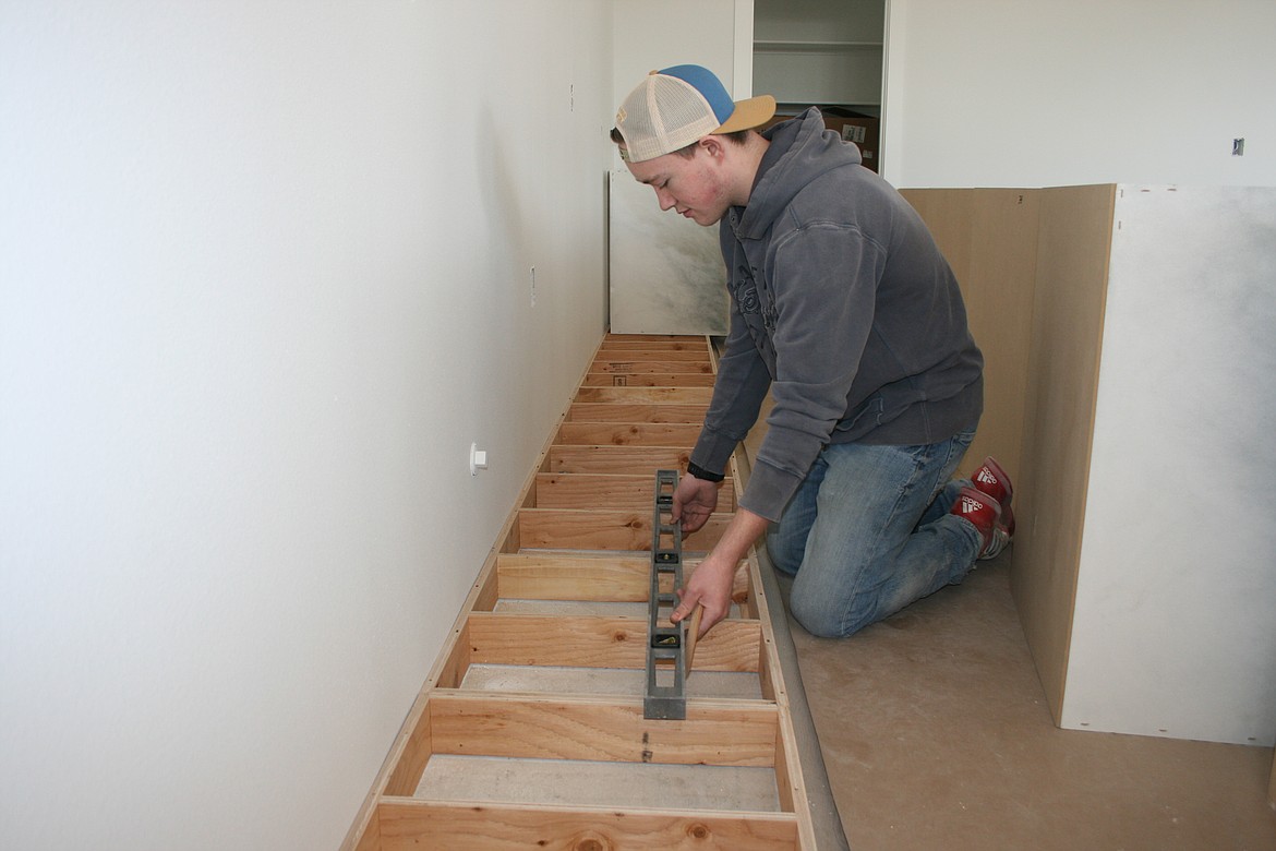 Brighton Roylance levels a cabinet base in the kitchen of a house under construction near Moses Lake.