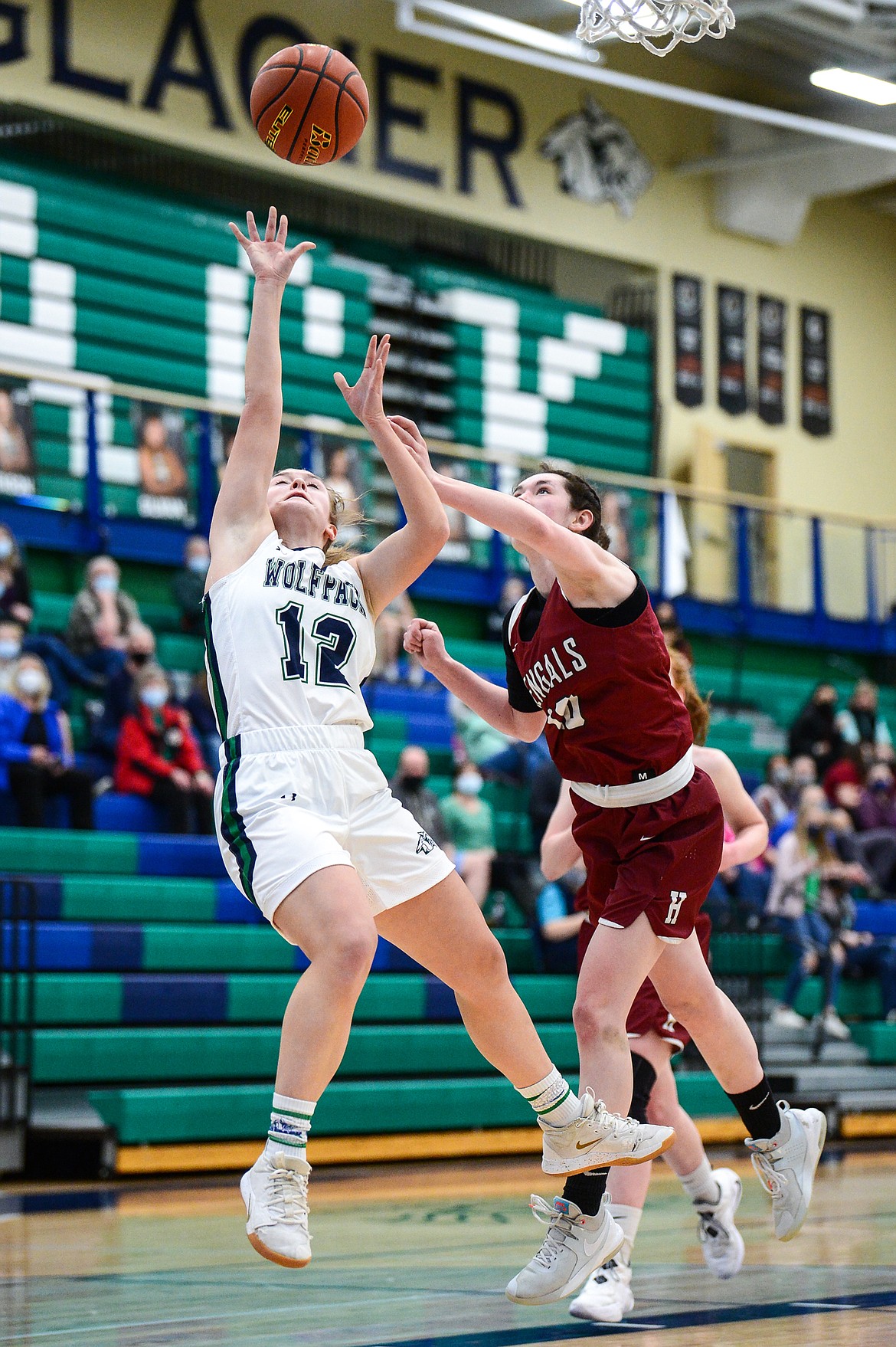 Glacier's Kenzie Williams (12) goes to the basket past Helena's Reegan Walsh (10) in the first half of a state AA play-in game at Glacier High School on Thursday. (Casey Kreider/Daily Inter Lake)