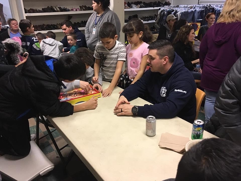 Firefighters for Kids Columbia Basin chapter president Jeremy Garrett sits with kids at the Union Gospel Misson women and children's shelter in Pasco, WA.