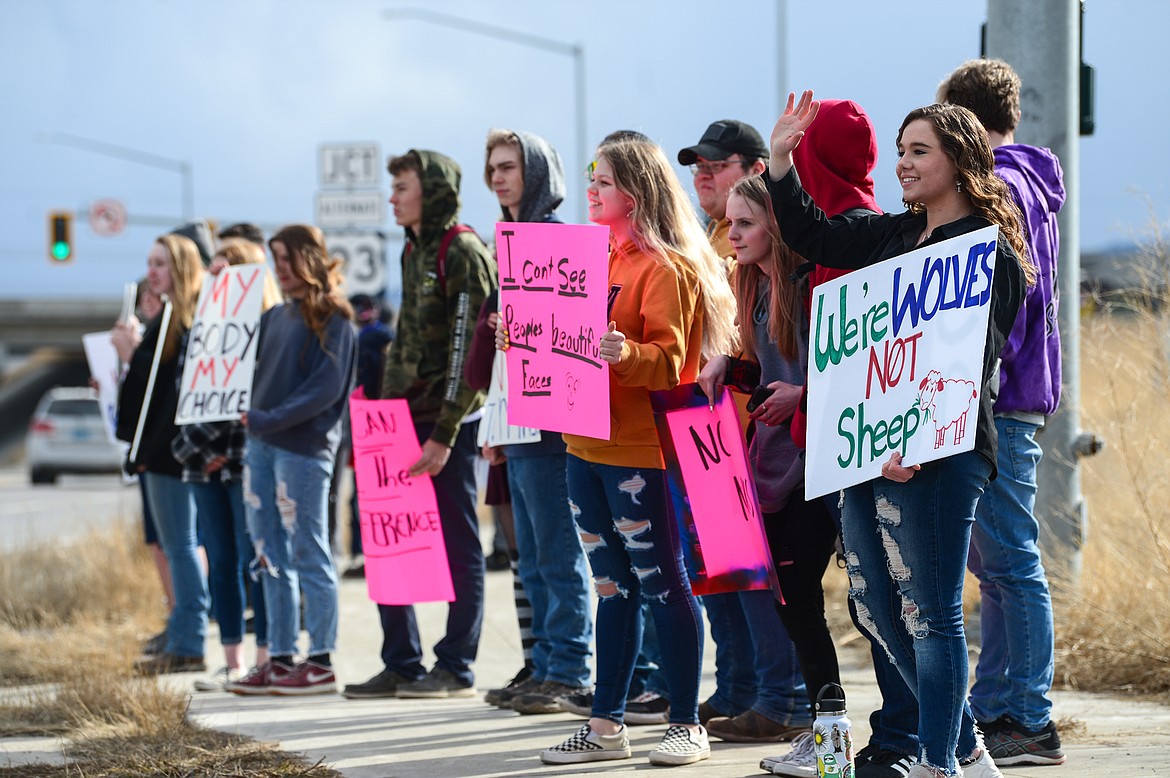 Kate Opre, right, a Glacier High School junior and co-organizer of a planned walkout in protest of Kalispell Public Schools' decision to continue a mask mandate, holds a sign and waves to passing motorists with fellow students outside Glacier High School on Tuesday. (Casey Kreider/Daily Inter Lake)
