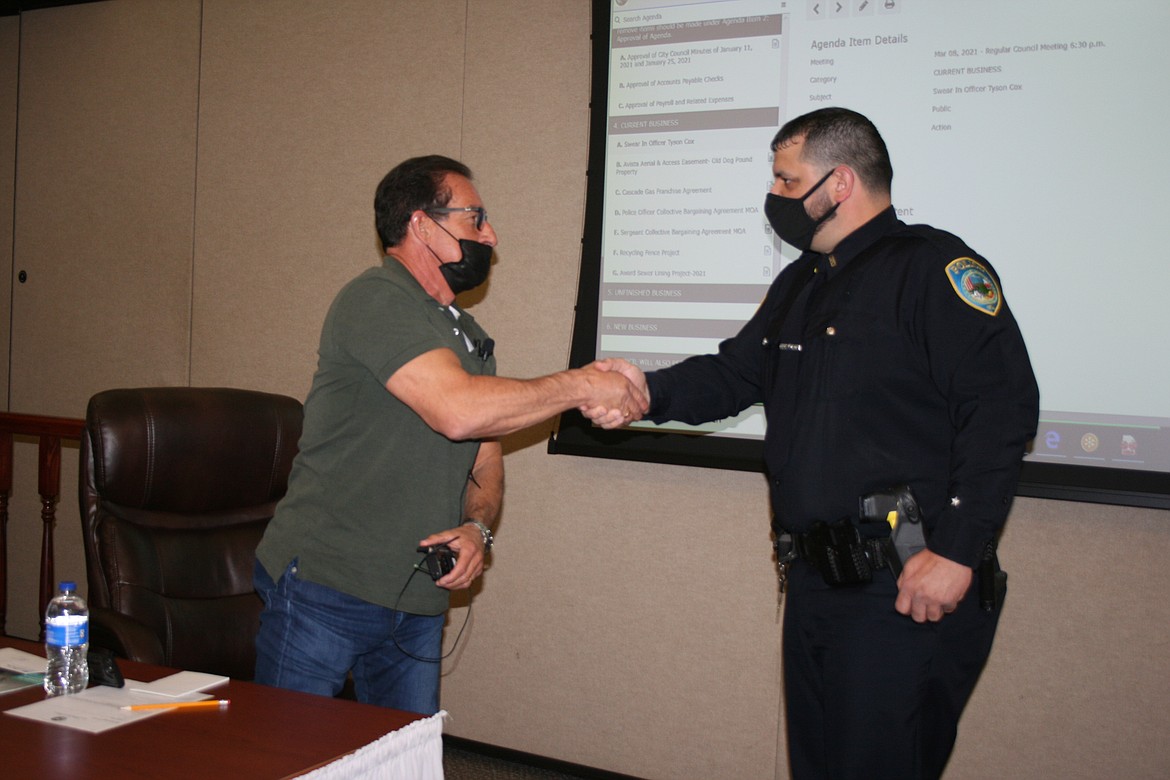 New Othello Police officer Tyson Cox (right) shakes hands with Othello City Council member Angel Garza during the council meeting Monday.