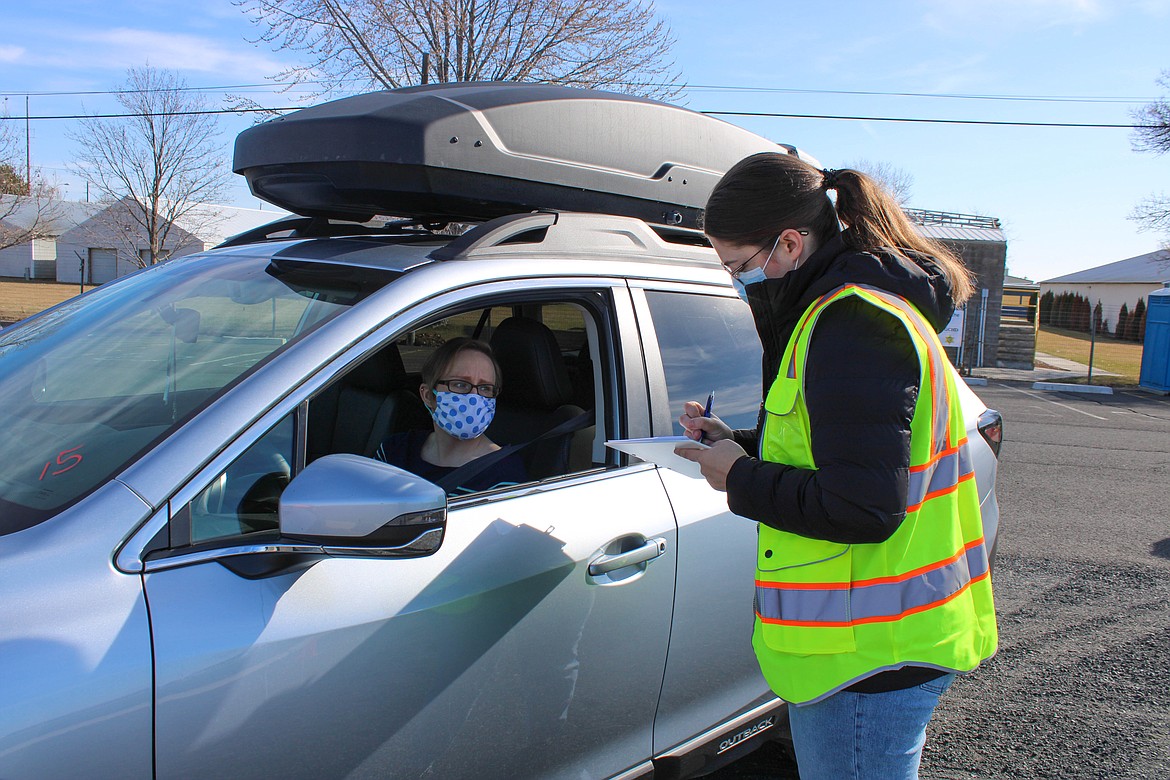 Volunteer Meg Lybbert, a professor at Eastern Washington University, right, gathers preliminary patient information at the Grant County Fairgrounds on Saturday.