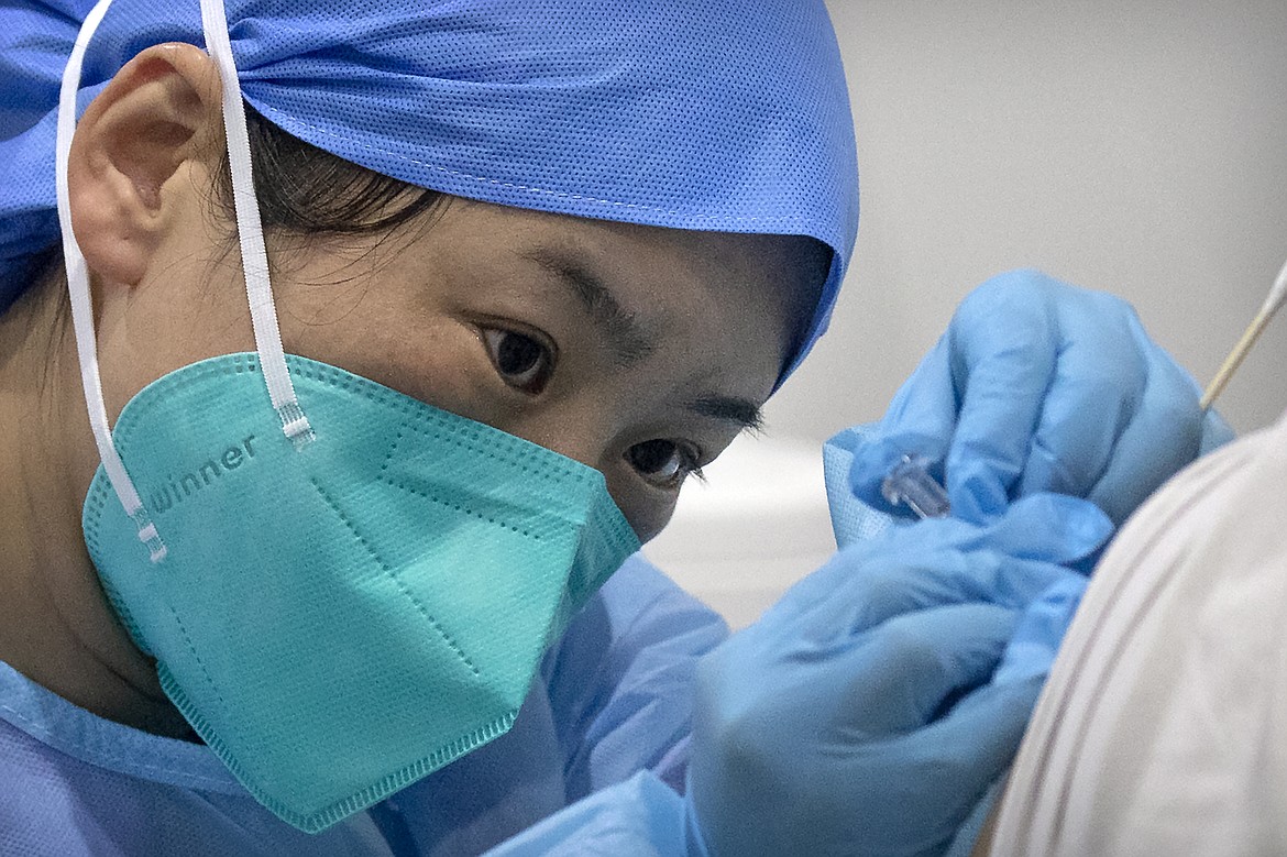 In this Jan. 15, 2021, file photo, a medical worker gives a coronavirus vaccine shot to a patient at a vaccination facility in Beijing. China is aiming to vaccinate 70-80% of its population by mid-2022, the head of the country's Center for Disease Control said Saturday.