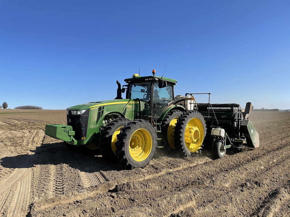 A tractor slowly sows seed potatoes in a field cultivated by Schneider Farms.