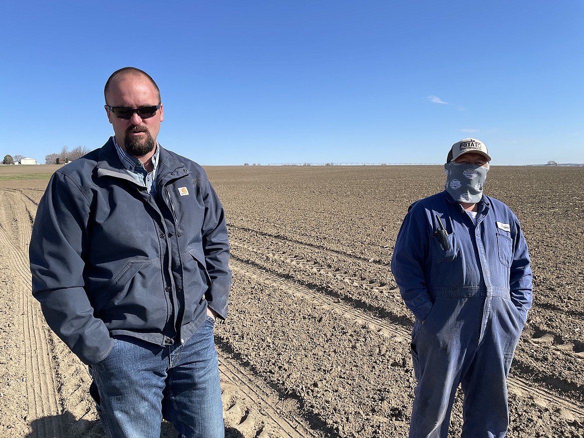 Grant Morris (left) and David Razo (right) oversee the planting of seed potatoes in one of the fields cultivated by Schneider Farms of Pasco. Razo, who has worked for Schneider Farms for 7 years, regularly checks to make sure the potatoes are planted at the right depth and the right spacing in order to ensure that they will grow properly.