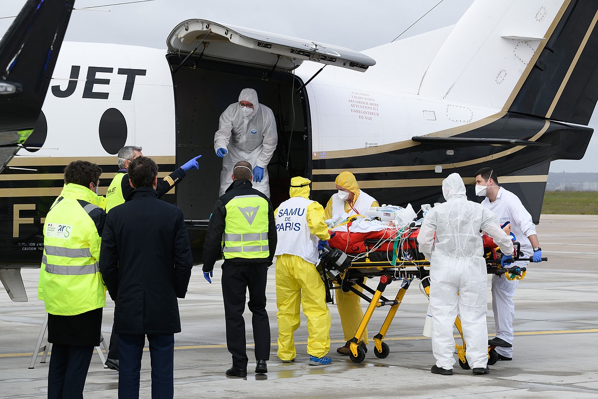 In this March 14, 2021, file photo, a patient infected with COVID-19 is loaded into a plane heading to a western France hospital, at Orly airport, south of Paris. Health experts say the surge in coronavirus cases in Europe should serve as a warning to the U.S. not to drop its safeguards too early.