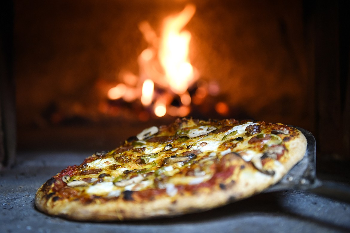One of Dog Creek Lodge's signature wood-fired pizzas made from locally sourced ingredients comes out of the oven on Wednesday. (Casey Kreider/Daily Inter Lake)
